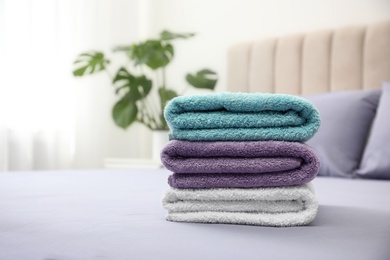 Stack of clean towels on bed indoors. Space for text