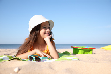 Photo of Cute little child lying at sandy beach on sunny day