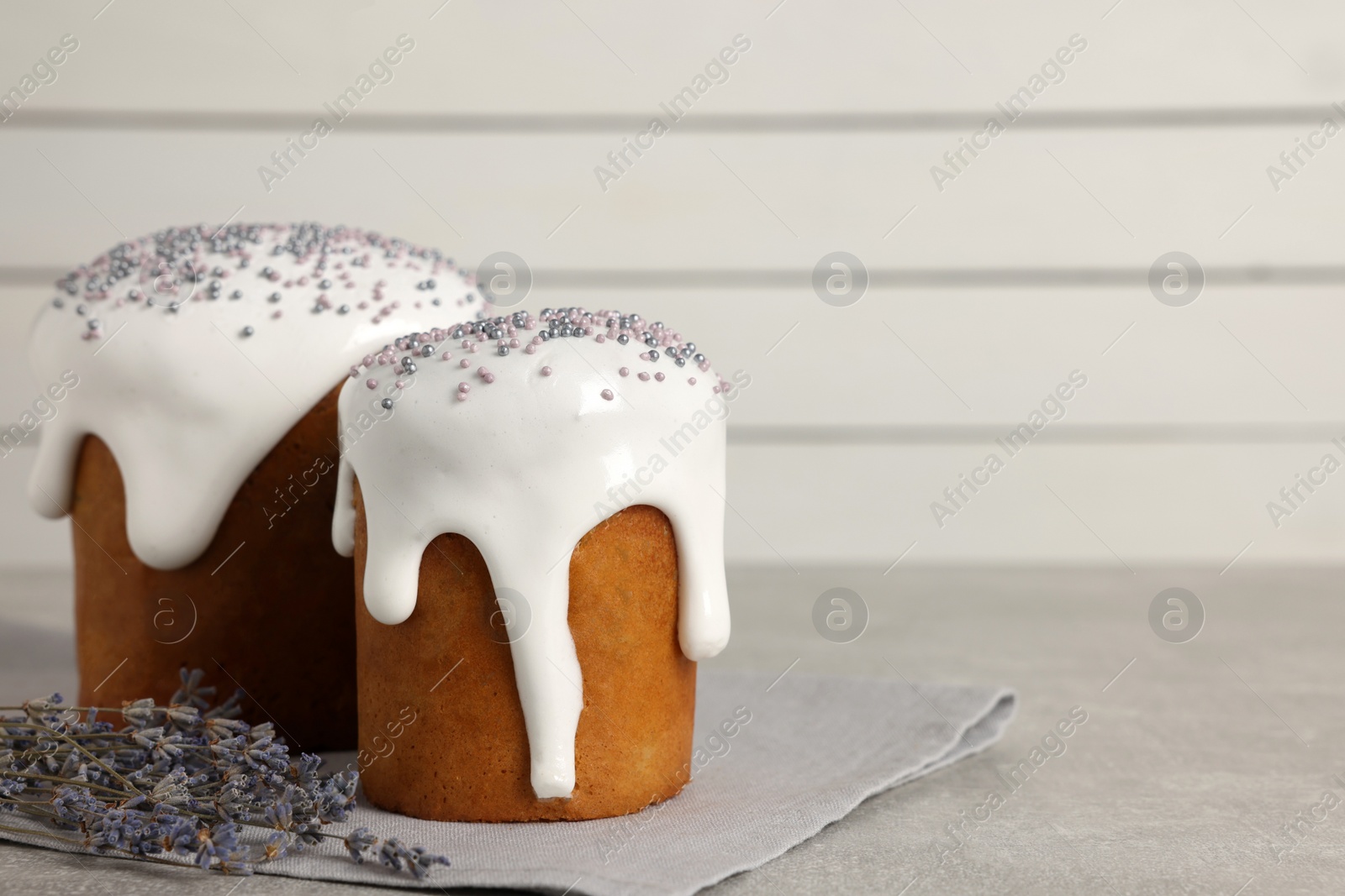 Photo of Tasty Easter cakes and lavender flowers on grey table. Space for text