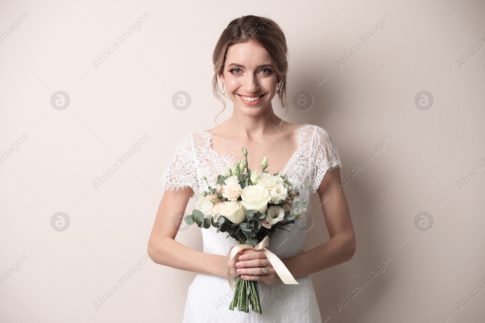 Photo of Young bride with beautiful wedding bouquet on beige background