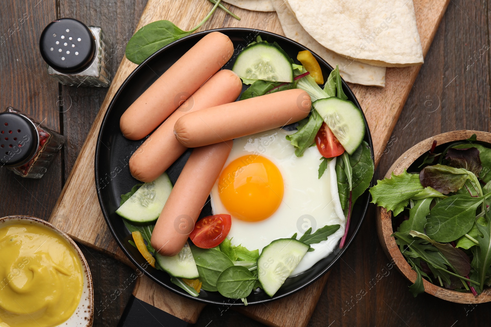 Photo of Delicious breakfast with boiled sausages and fried egg served on wooden table, flat lay