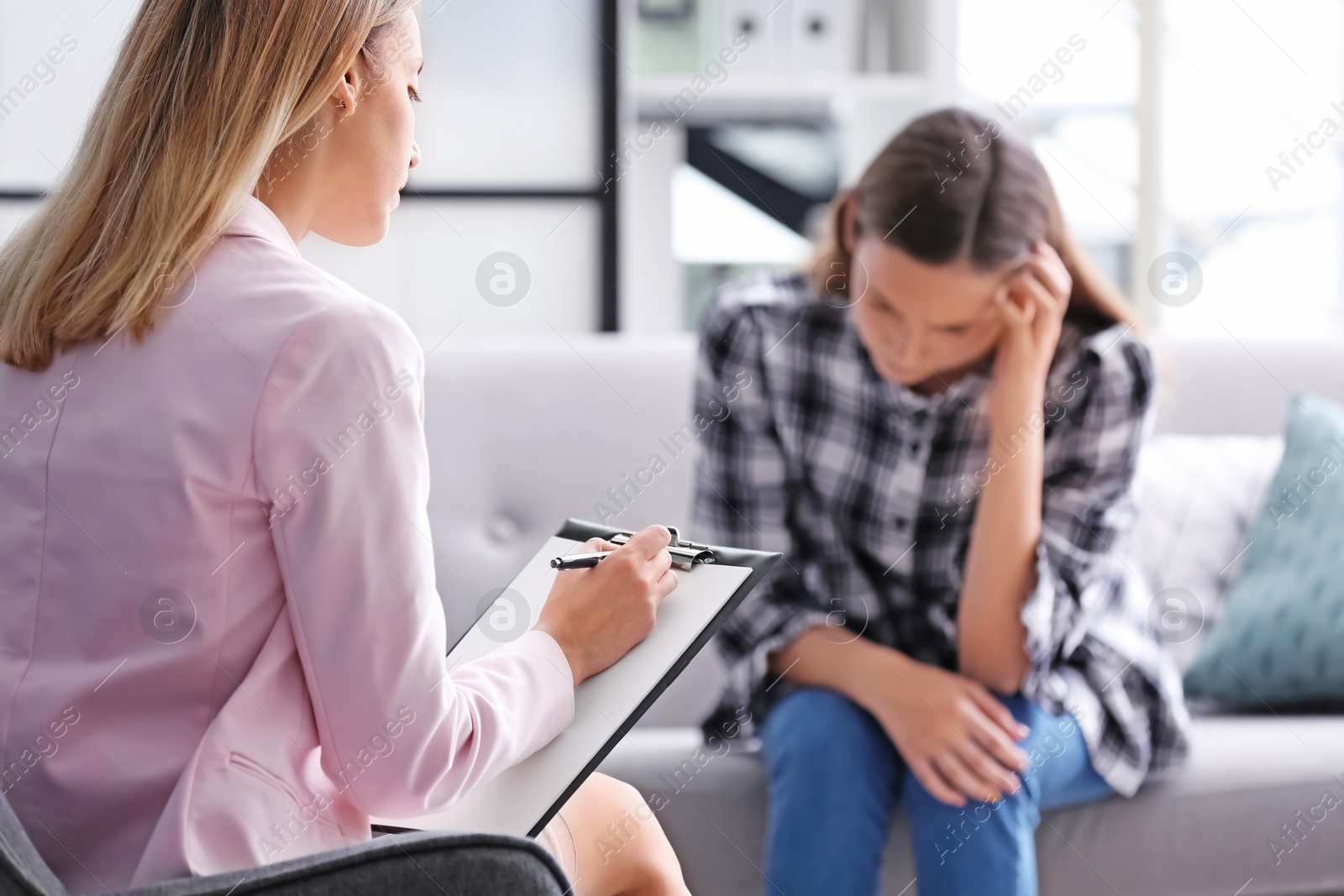 Photo of Child psychologist working with teenage girl in office