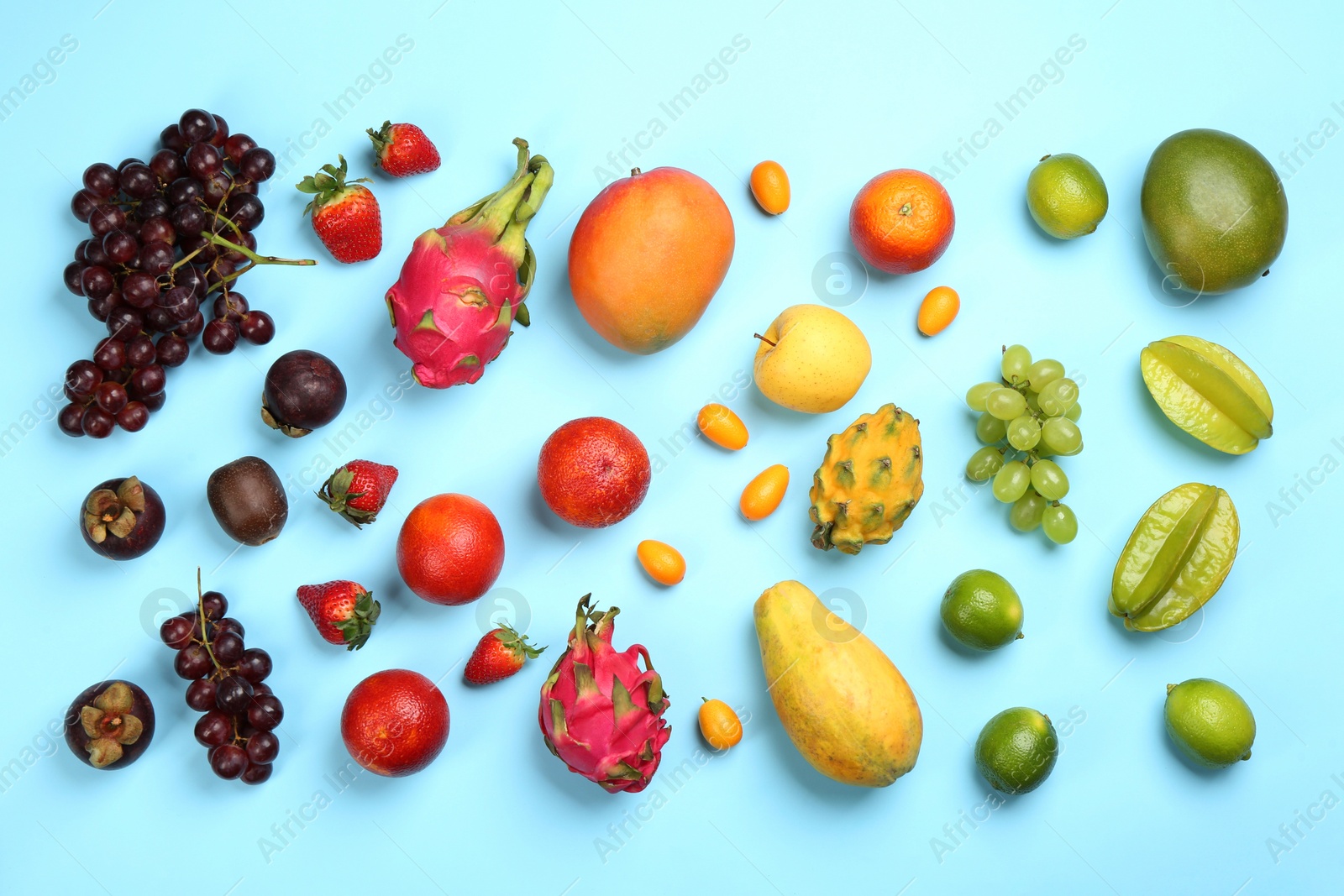 Photo of Many different delicious exotic fruits on light blue background, flat lay