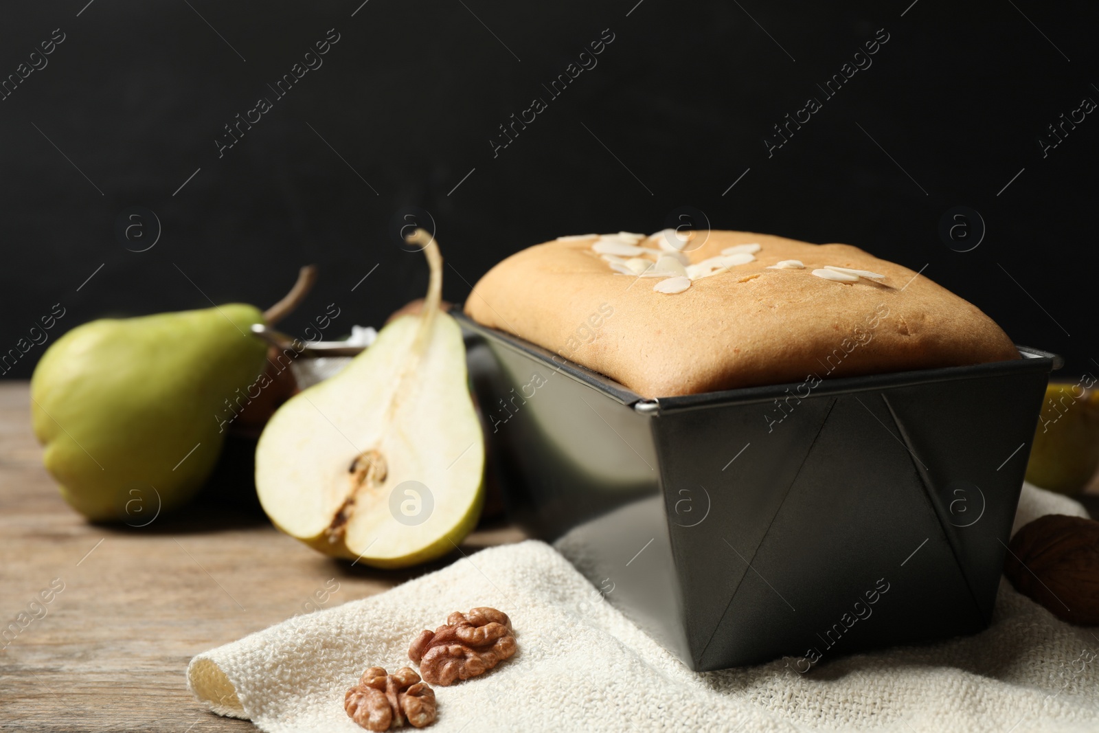 Photo of Tasty bread with almond flakes and pears on wooden table, closeup. Homemade cake