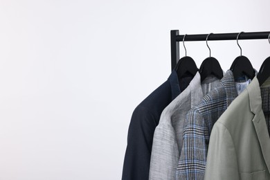 Photo of Dry-cleaning service. Many different clothes hanging on rack against white background, space for text