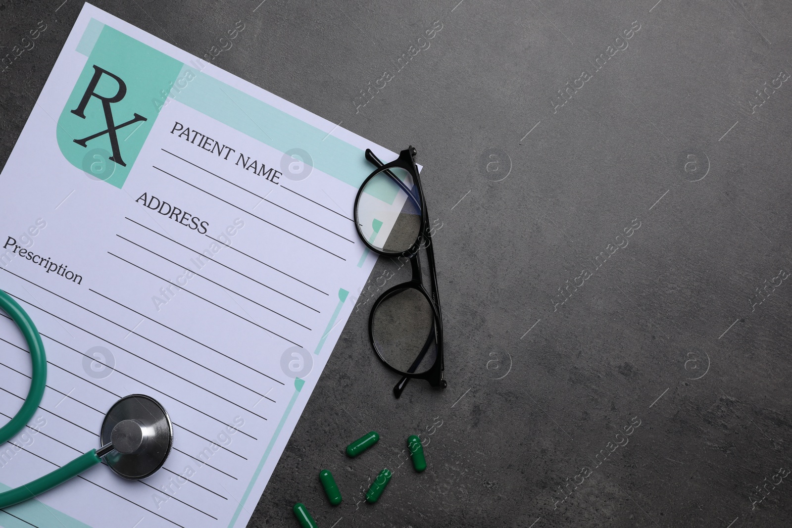 Photo of Medical prescription form, stethoscope, pills and glasses on dark grey table, flat lay. Space for text