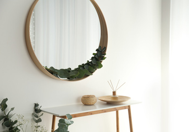 Round mirror with wooden frame in light room