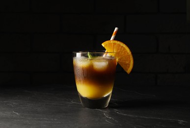 Photo of Tasty refreshing drink with coffee and orange juice on grey table against dark background