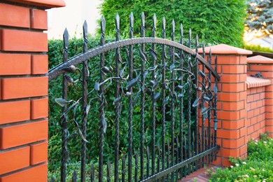 Photo of Beautiful brick fence with iron railing outdoors