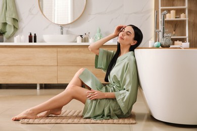 Photo of Beautiful young woman sitting near tub in bathroom