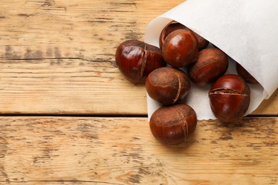 Photo of Fresh edible sweet chestnuts on wooden table, top view. Space for text