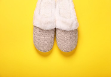 Photo of Pair of beautiful soft slippers on yellow background, top view
