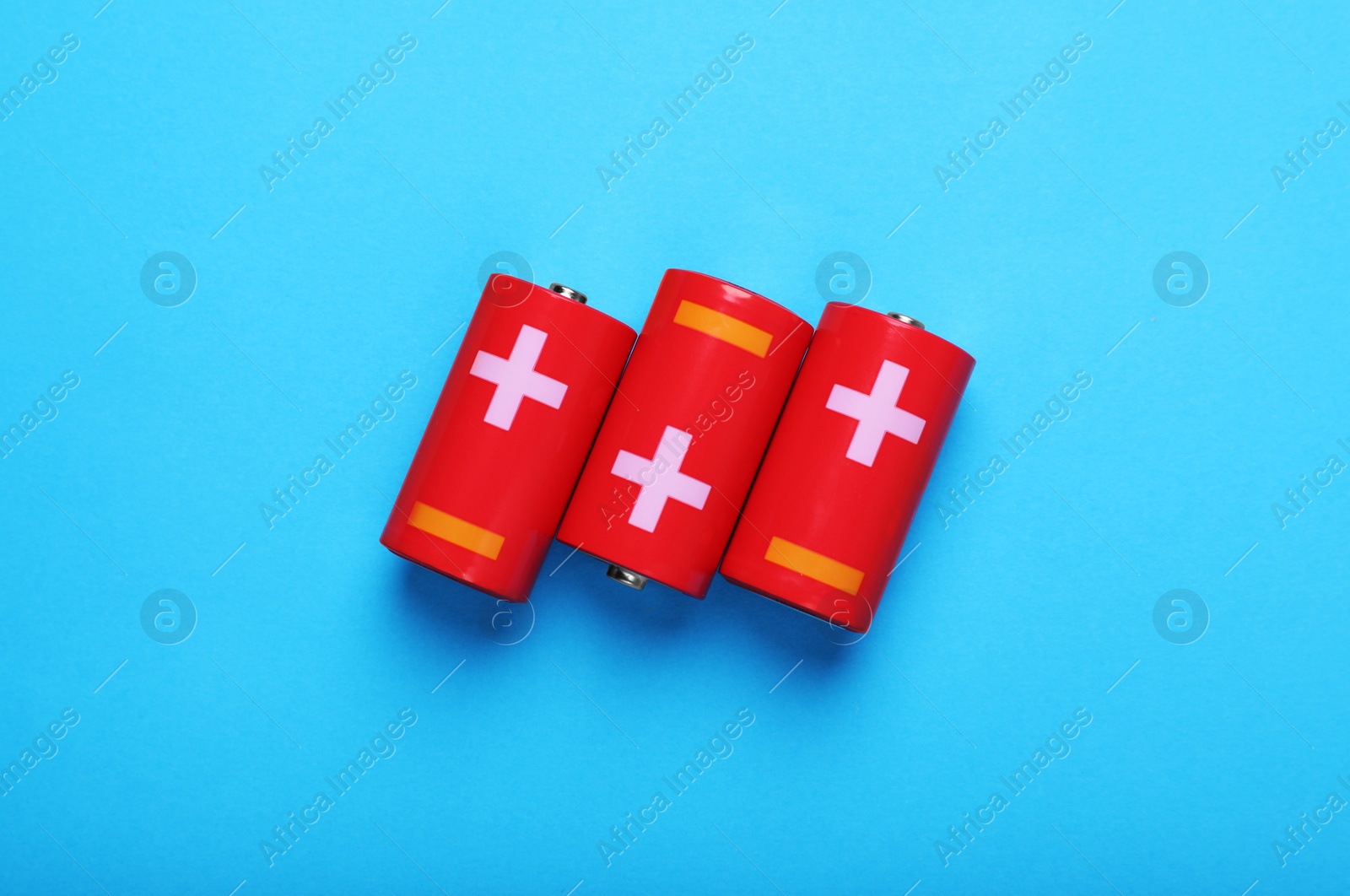 Photo of New C size batteries on light blue background, flat lay