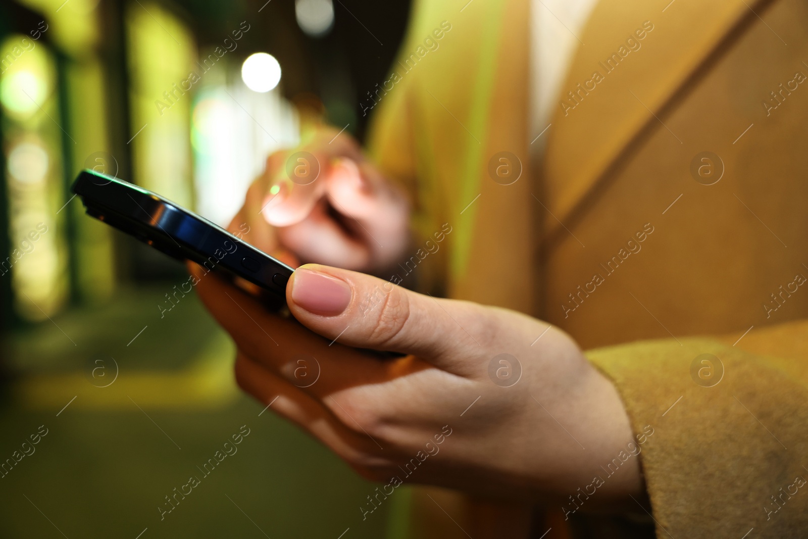 Photo of Woman using smartphone on night city street, closeup