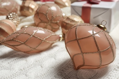 Beautiful Christmas tree baubles on white knitted fabric, closeup