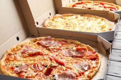 Carton boxes with delicious pizzas on wooden background