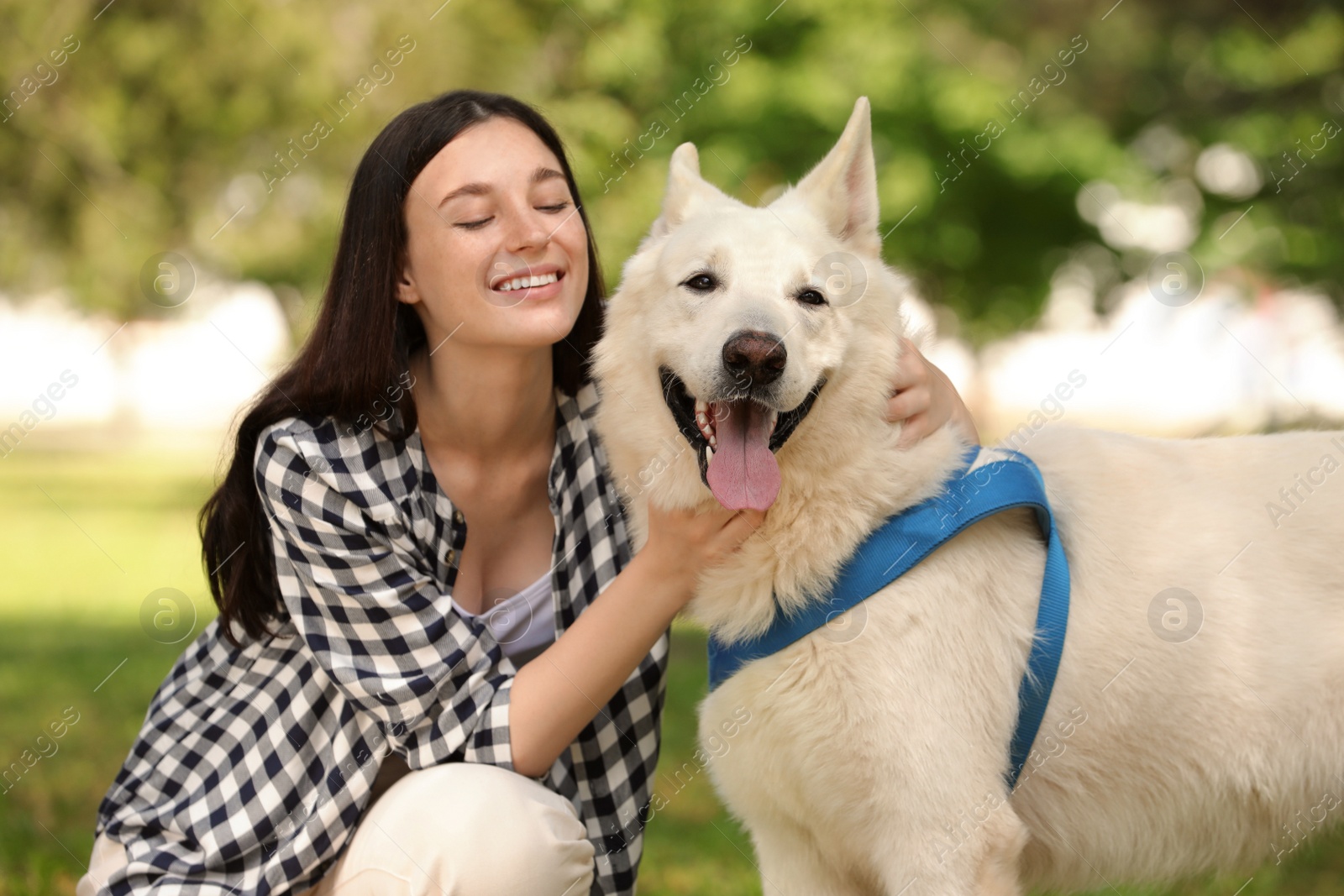 Photo of Teenage girl hugging her white Swiss Shepherd dog in park