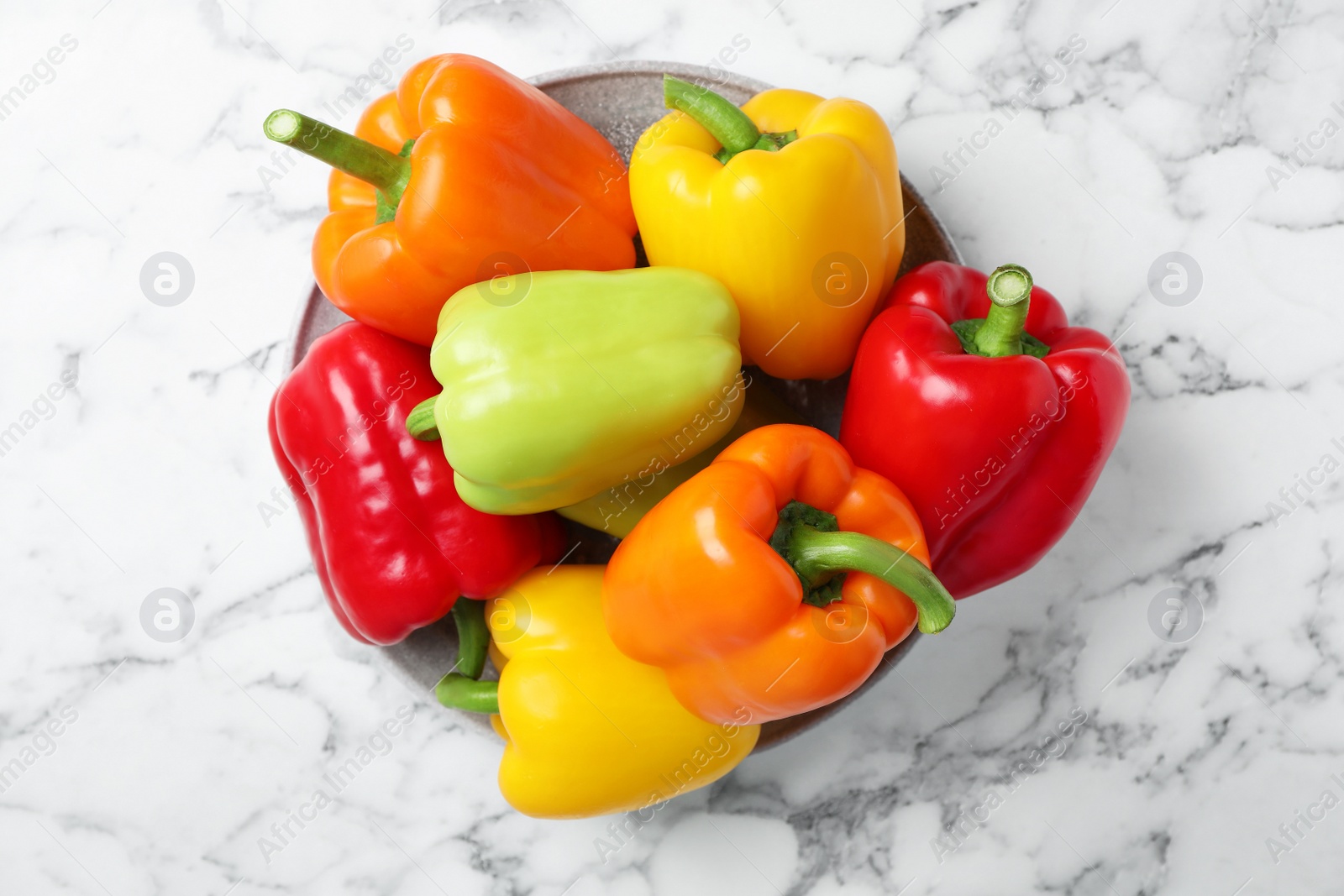 Photo of Plate with fresh bell peppers on marble table, top view