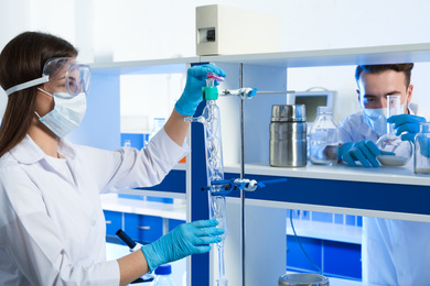 Scientist pouring liquid through glass distillation condenser indoors. Laboratory analysis