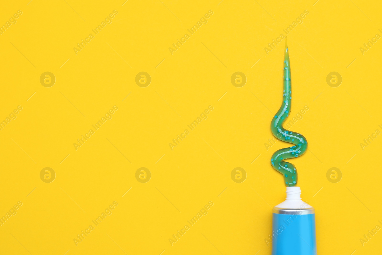 Photo of Tube of toothpaste on yellow background, flat lay. Space for text