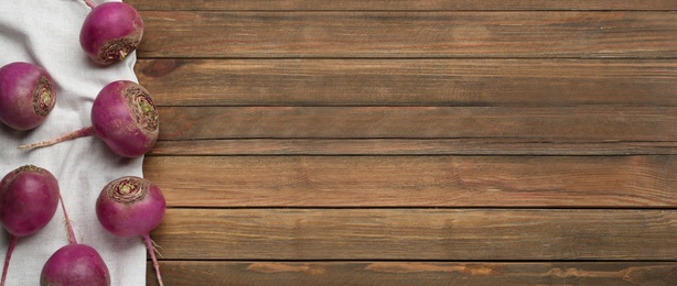 Image of Red turnips on wooden table, flat lay. Space for text