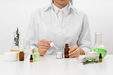 Photo of Female dermatologist creating skin care product at table, closeup