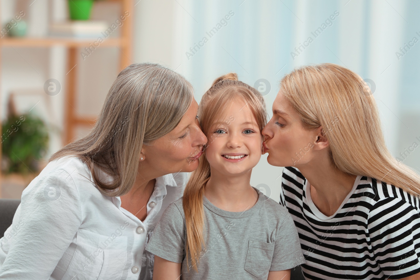 Photo of Three generations. Happy grandmother, her daughter and granddaughter at home