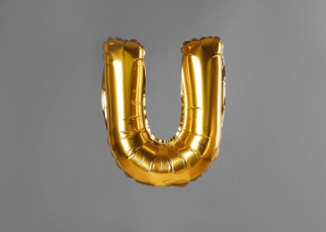 Golden letter U balloon on grey background