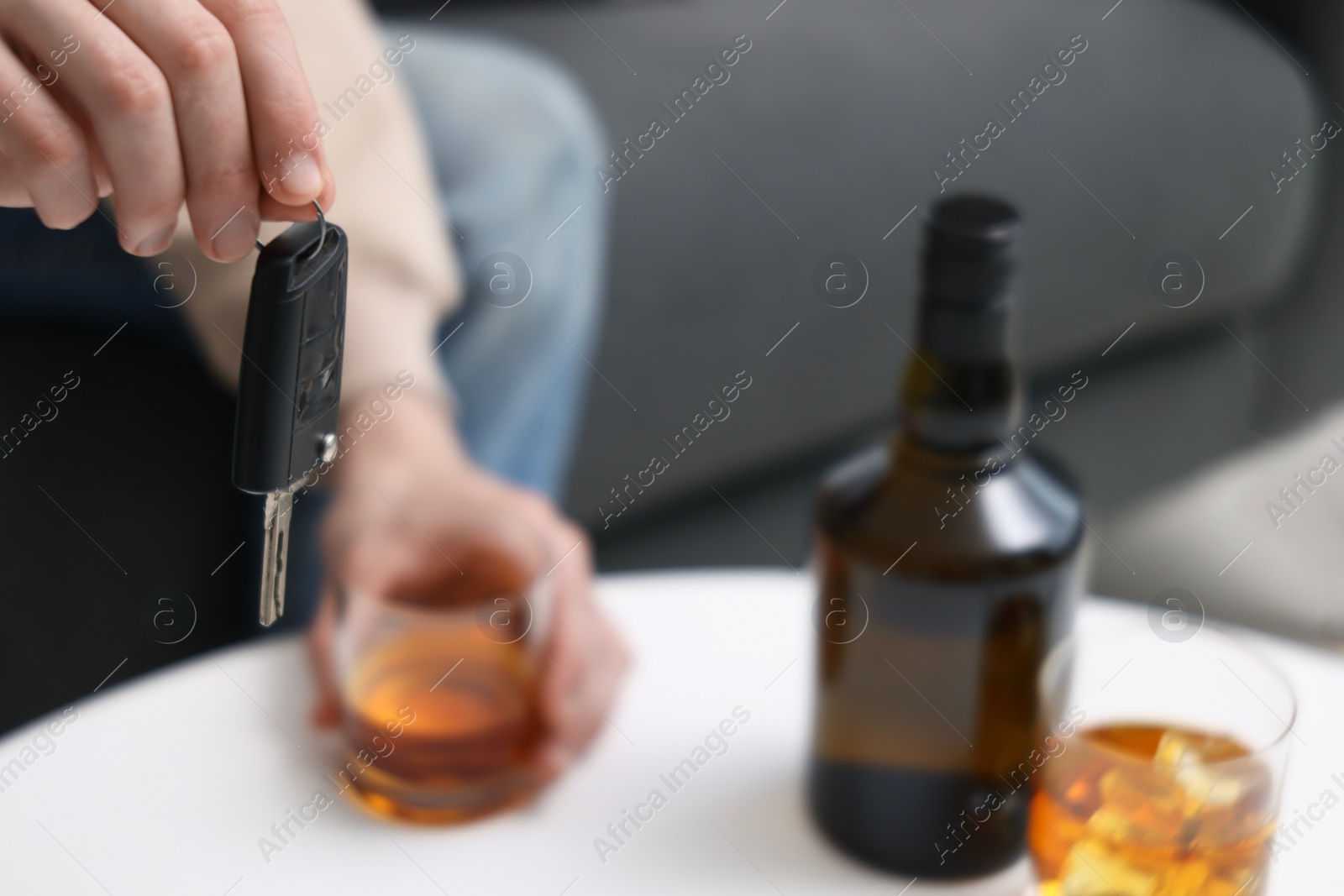 Photo of Man with glass of alcoholic drink and car keys at table, closeup. Don't drink and drive concept