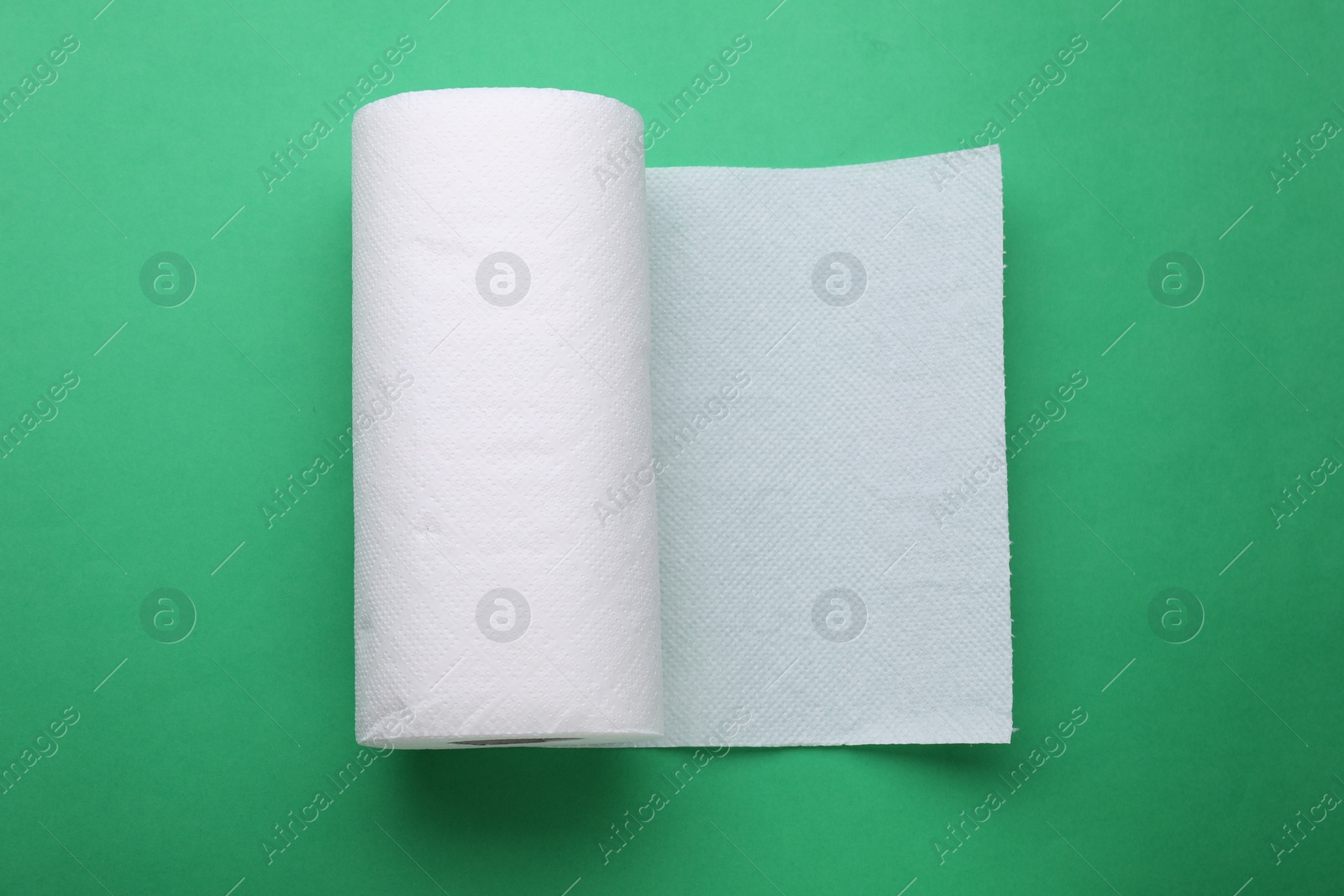 Photo of Roll of tissue towels on green background, top view