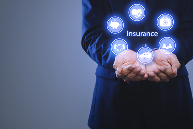 Image of Businessman holding different icons on grey background, closeup with space for text. Insurance concept