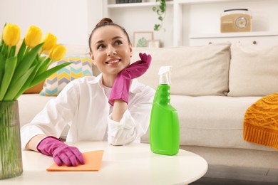 Photo of Spring cleaning. Young woman tidying up living room at home