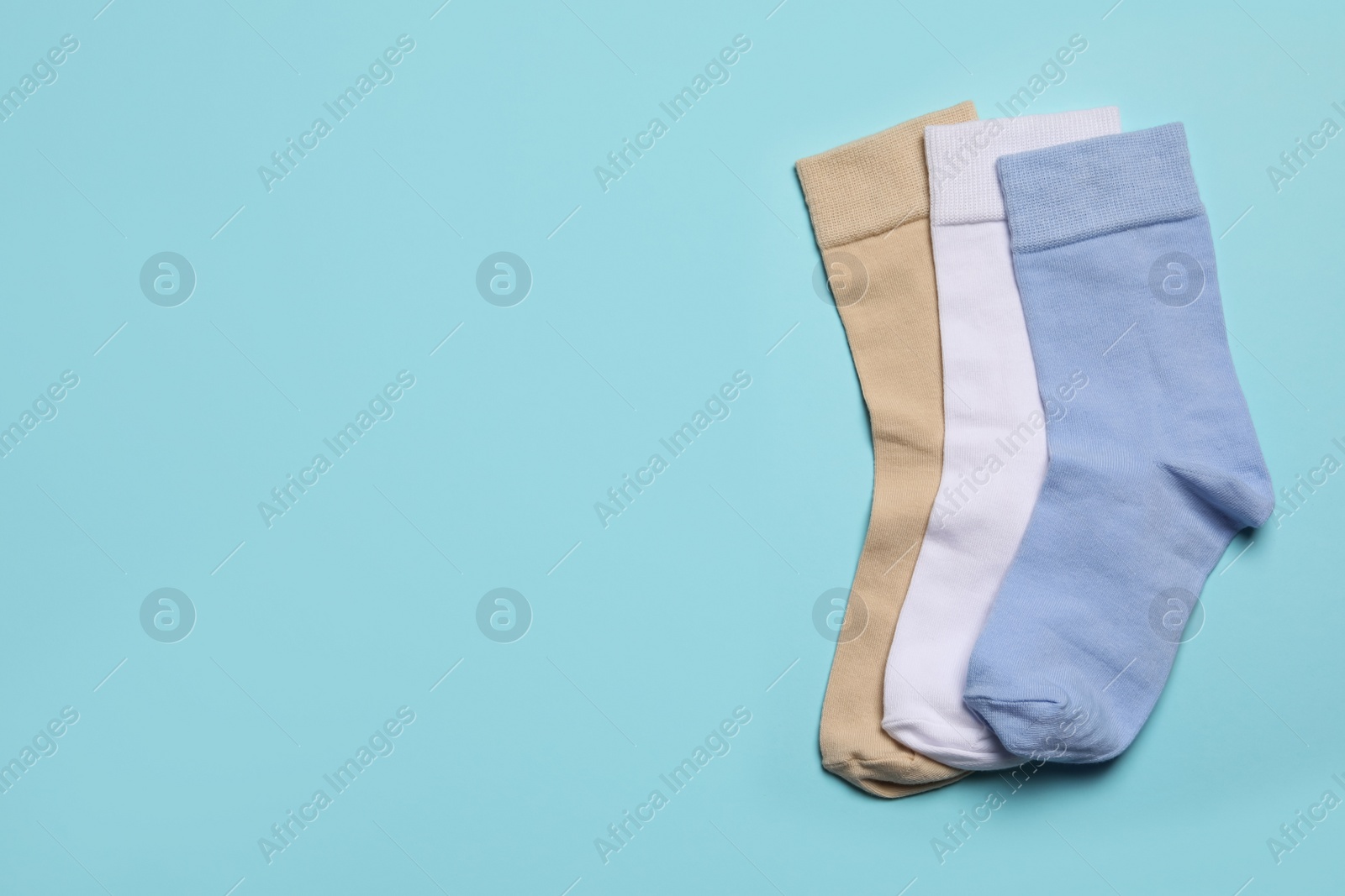 Photo of Different socks on light blue background, flat lay. Space for text