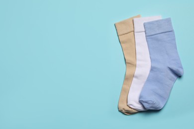 Different socks on light blue background, flat lay. Space for text