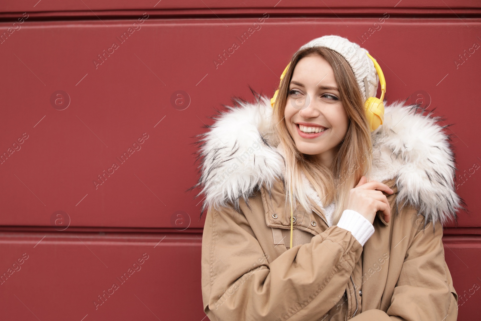 Photo of Young woman with headphones listening to music near color wall. Space for text