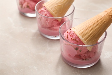 Delicious pink ice cream in wafer cones served on light table, closeup. Space for text