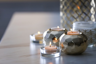 Photo of Burning candles in holders on white marble table indoors