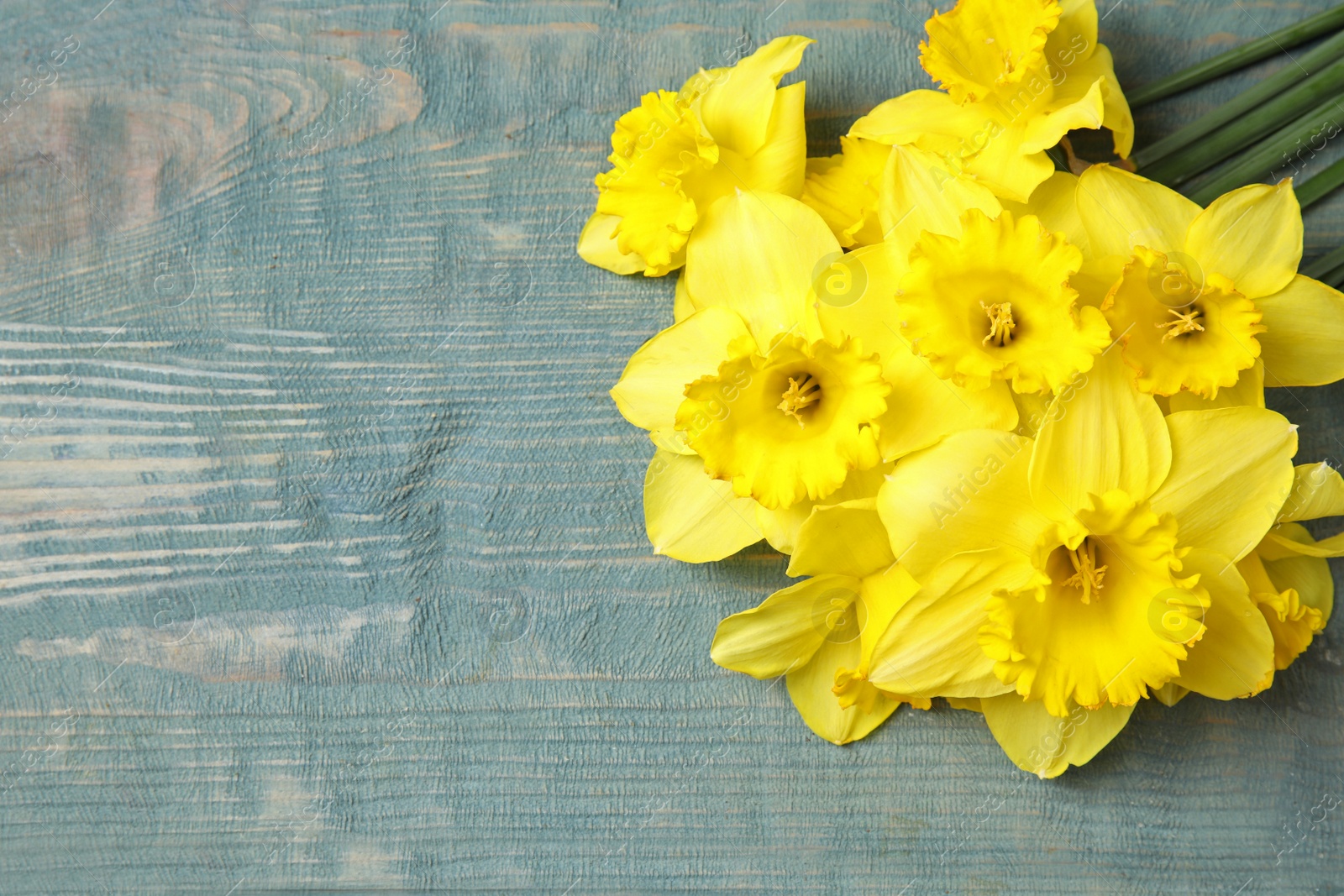 Photo of Bouquet of daffodils on wooden background, top view with space for text. Fresh spring flowers