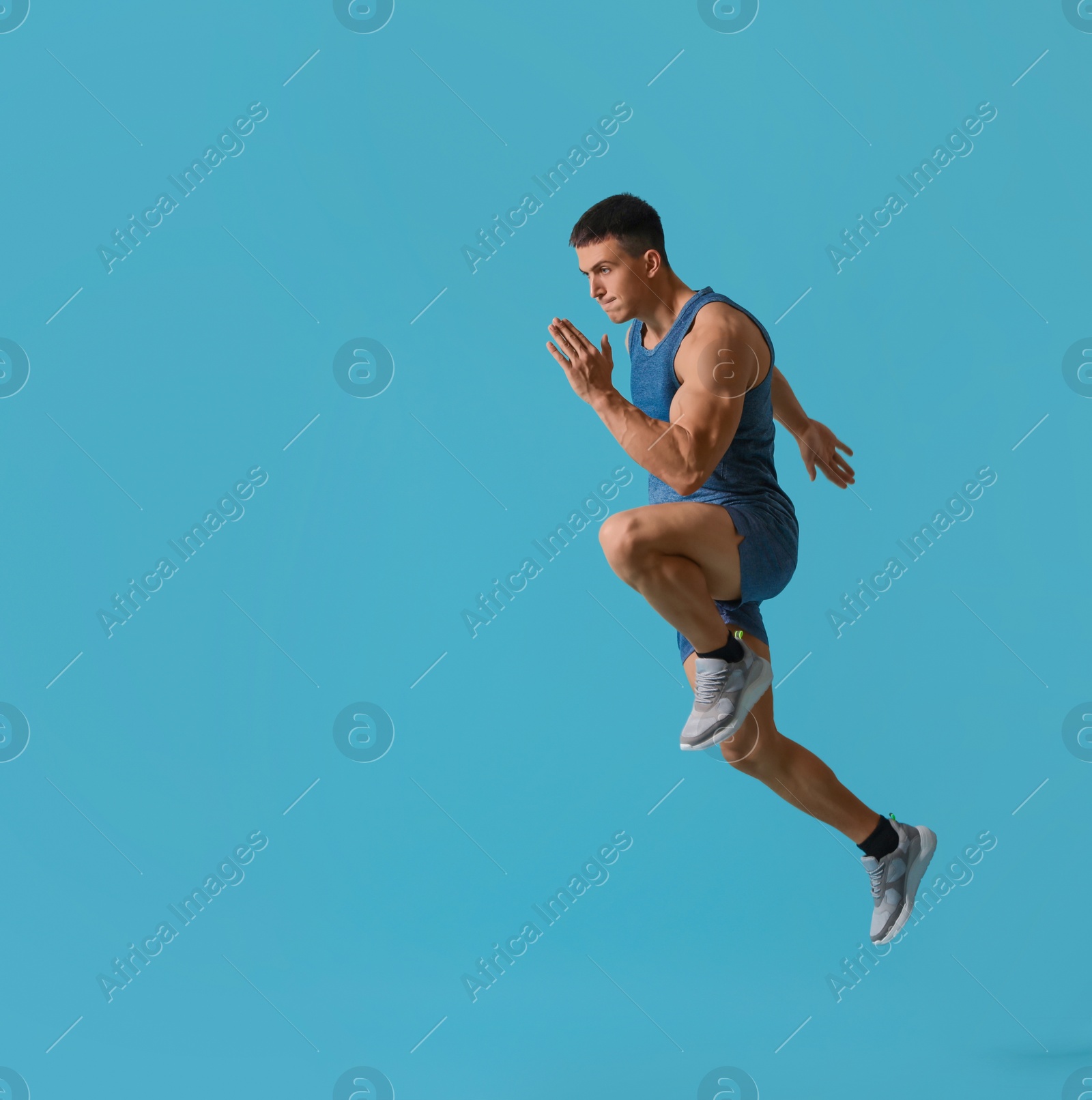 Photo of Athletic young man running on turquoise background, side view