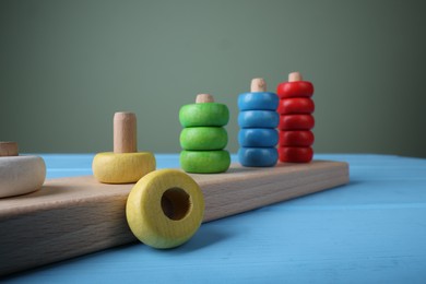 Photo of Stacking and counting game pieces on light blue wooden table against grey wall, closeup. Motor skills development