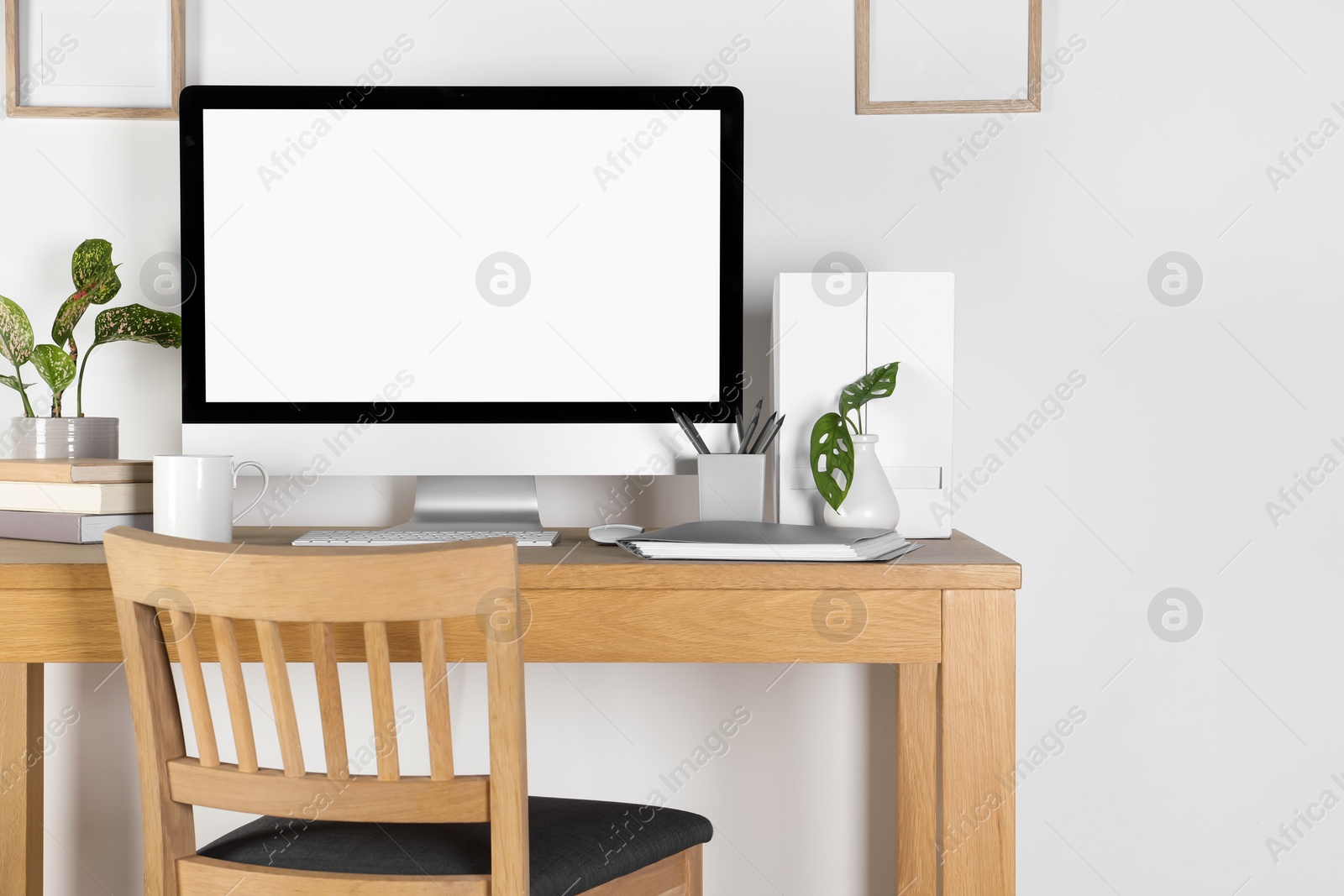 Photo of Home workplace. Computer, stationery and houseplants on wooden desk