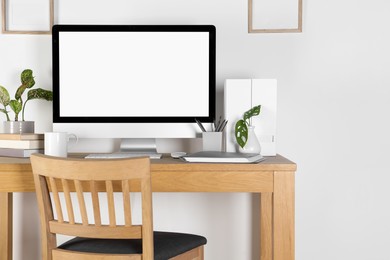 Photo of Home workplace. Computer, stationery and houseplants on wooden desk