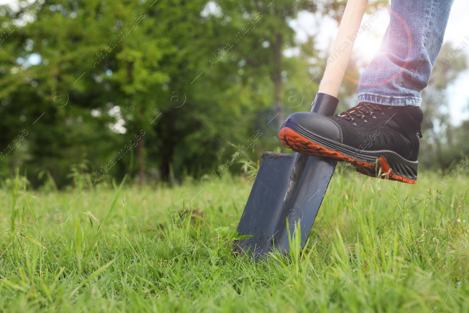 Photo of Worker digging soil with shovel outdoors, closeup