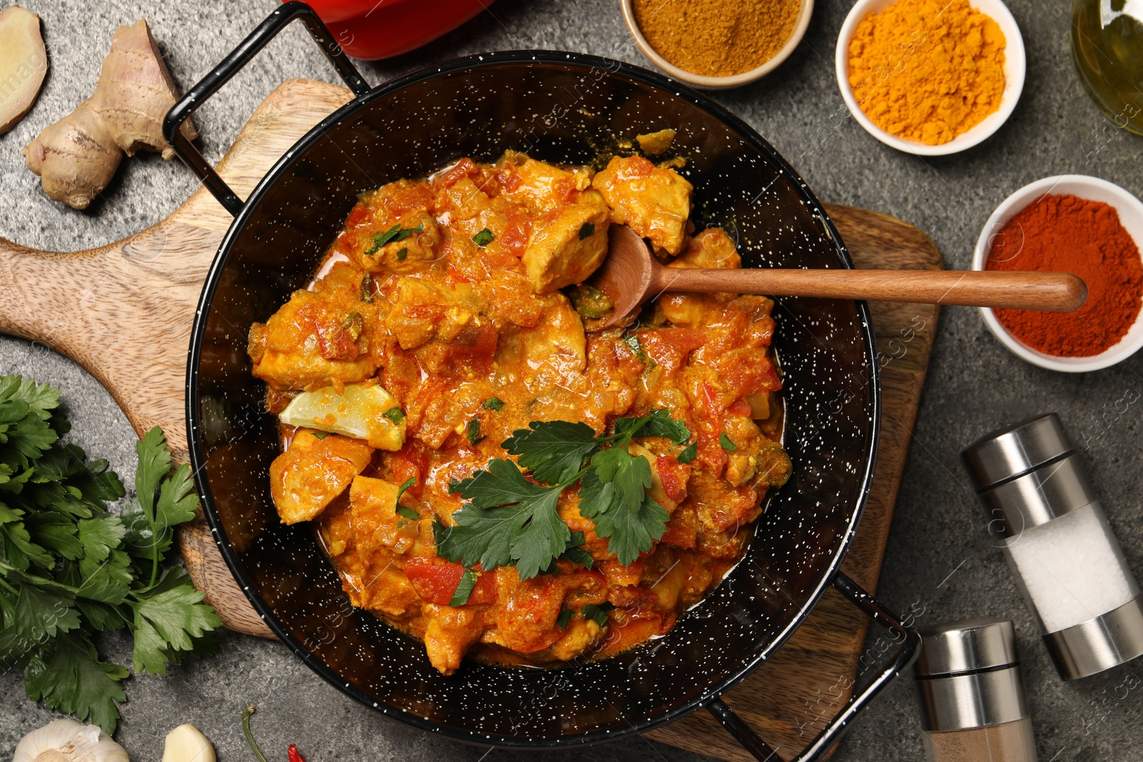 Photo of Delicious chicken curry and ingredients on grey table, flat lay