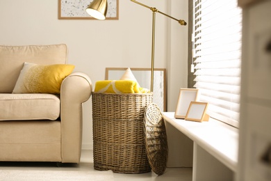 Basket with soft plaid and pillows in living room interior