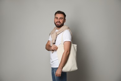 Happy young man with eco bag on light background