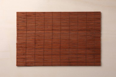 Photo of Bamboo mat on beige table, top view. Space for text