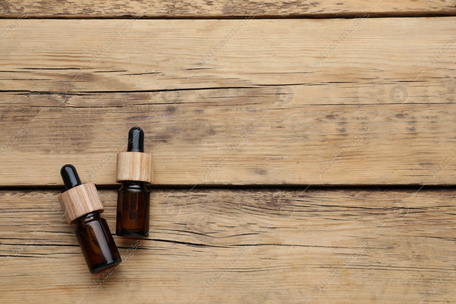 Photo of Bottles of essential oil on wooden table, flat lay. Space for text