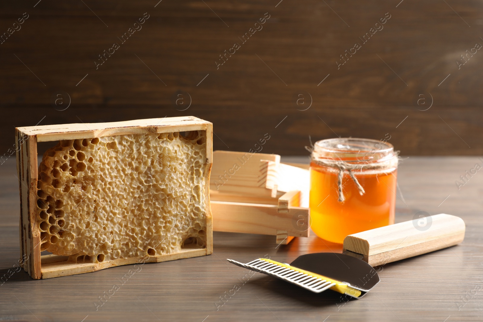 Photo of Composition with honeycomb and beekeeping equipment on wooden table