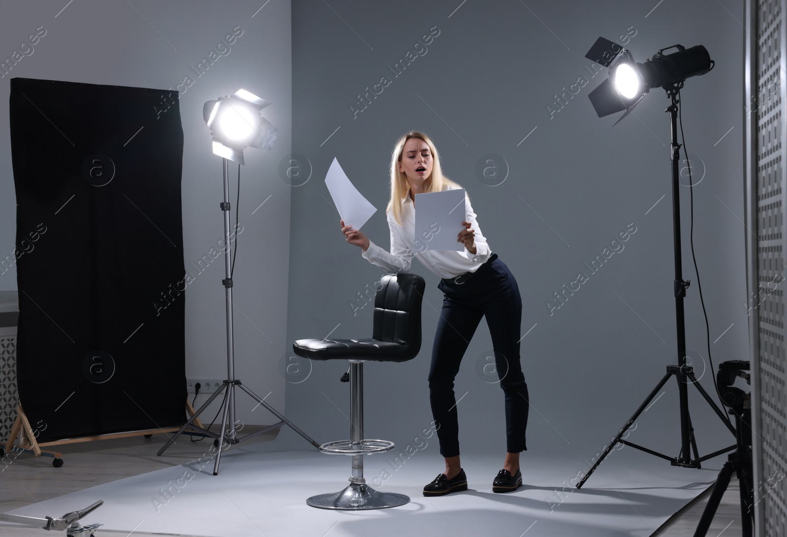 Photo of Casting call. Emotional woman performing against grey background in studio